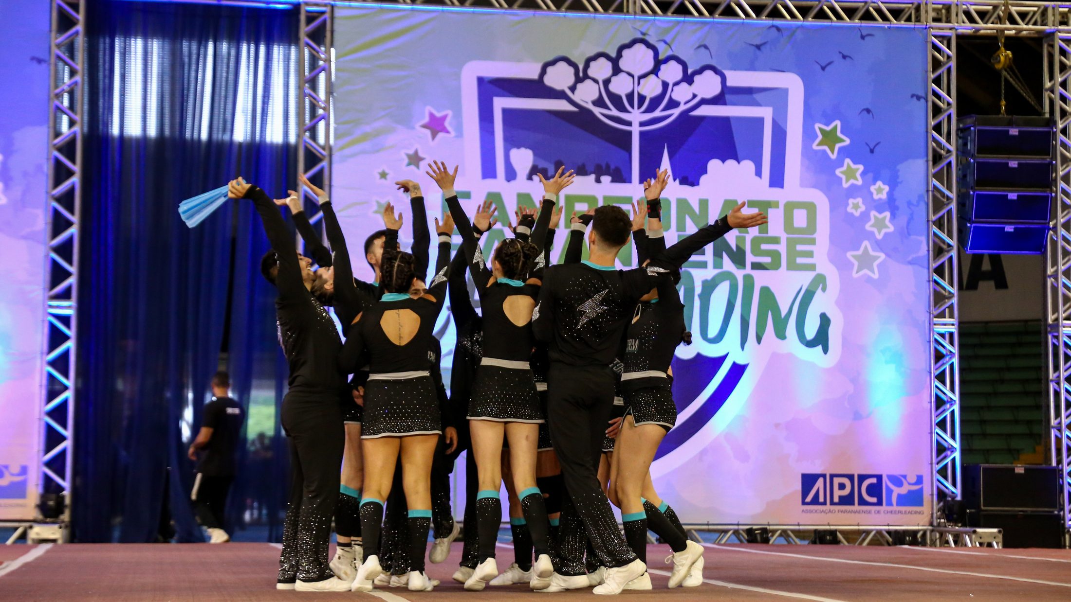 Equipe da Storm All Star reunida no tablado do Campeonato Paranaense de Cheerleading, com os braços erguidos